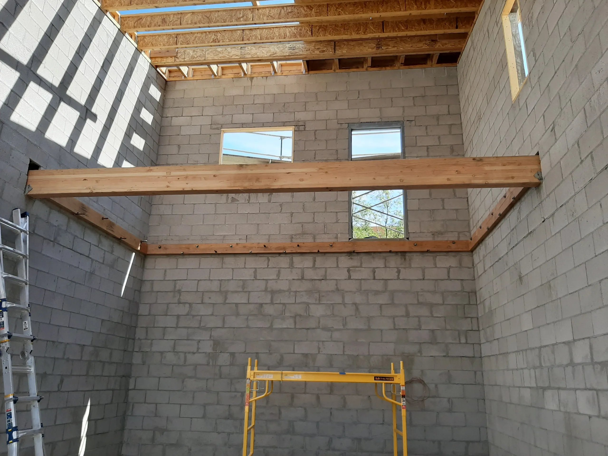 Unfinished interior with concrete block walls and wooden roof framing