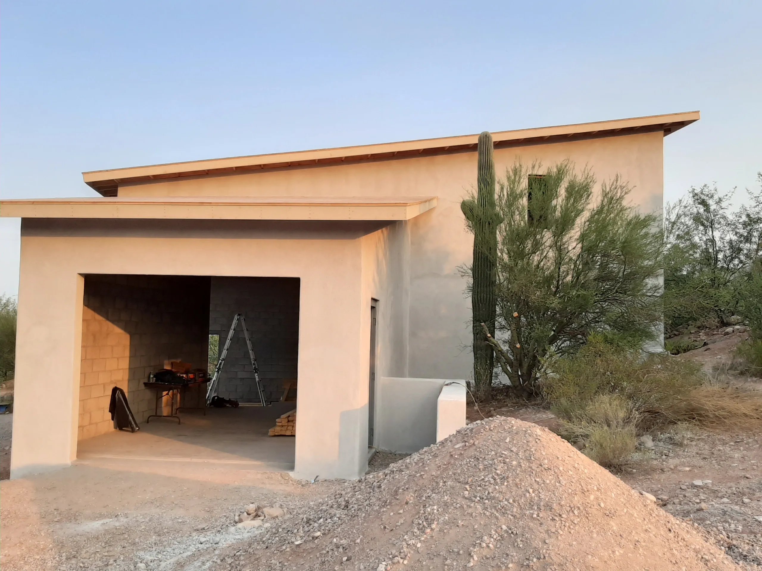 Desert building with open garage, cactus, and construction materials