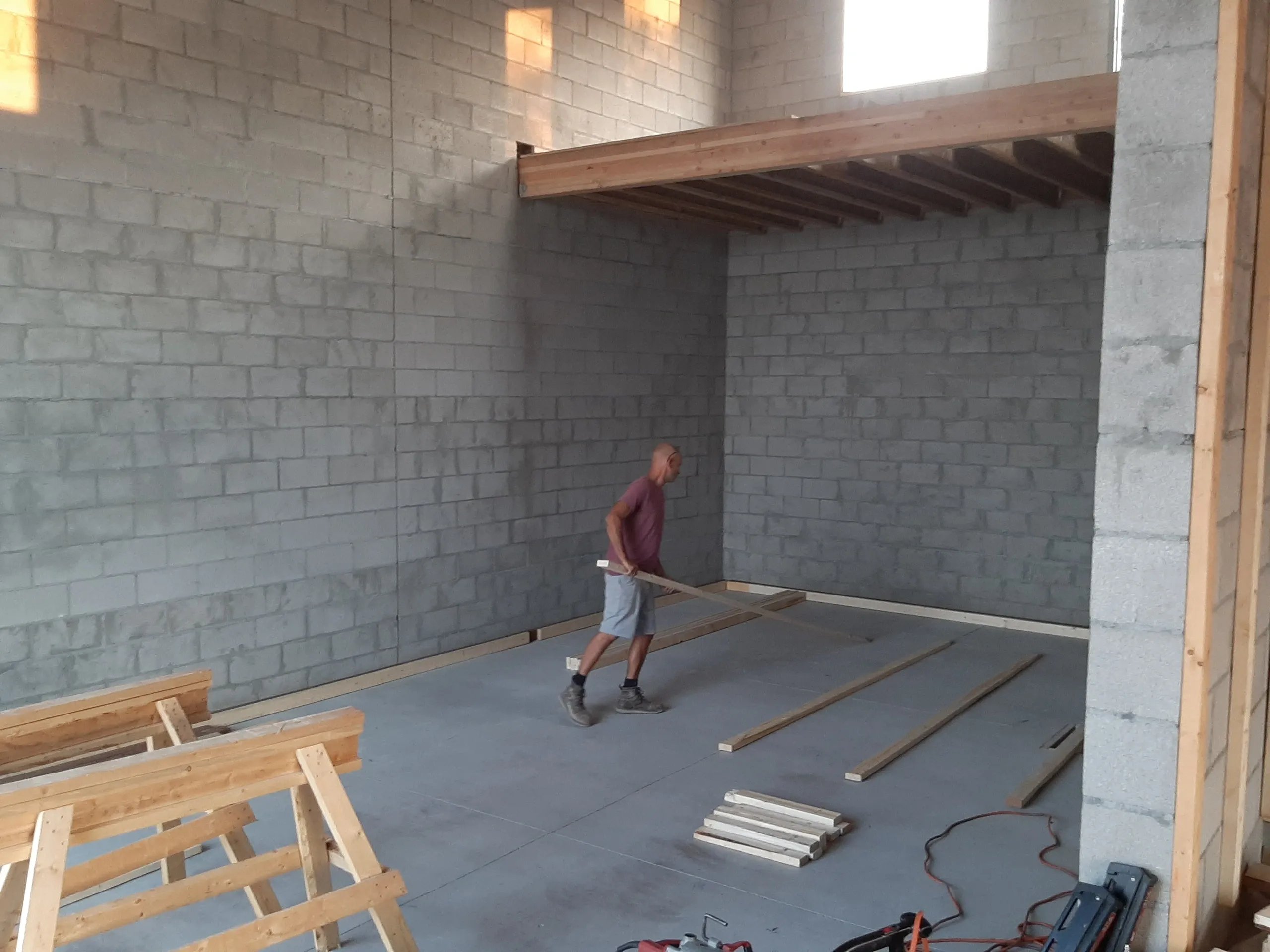 Construction worker installing wooden floor joists in concrete building